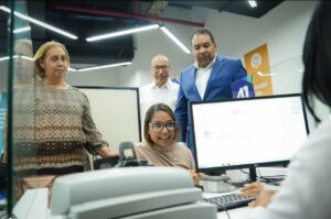 Fotografía de autoridades interactuando con personal en un área de atención al ciudadano dentro de una oficina institucional.