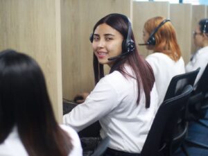 Personal de atención telefónica trabajando con auriculares y computadoras en un centro de contacto.